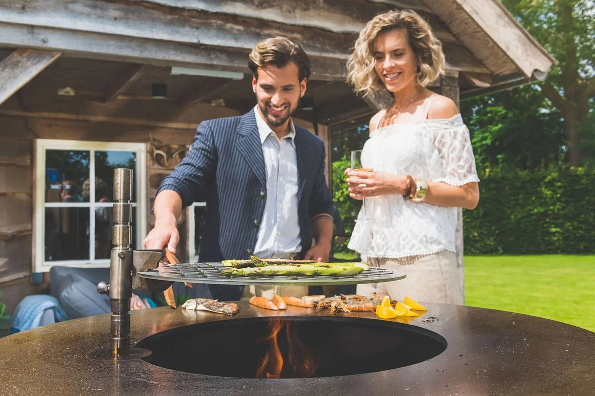 Crevettes, poisson et légumes sur la plaque de cuisson du brasero FIQ XL Artola en extérieur