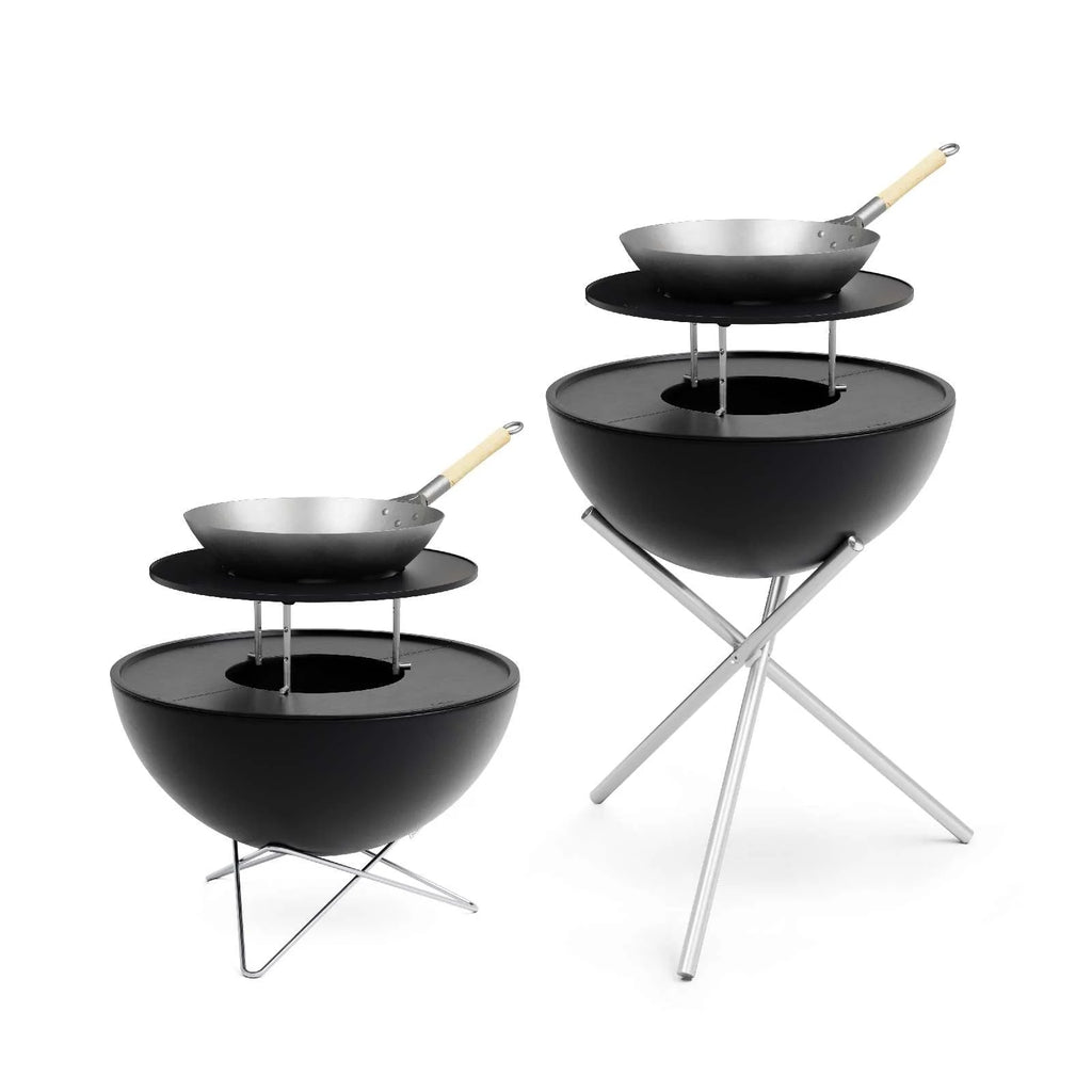 Gril en forme de bol noir avec des pieds en métal et un wok sur le dessus, conçu par Weber.