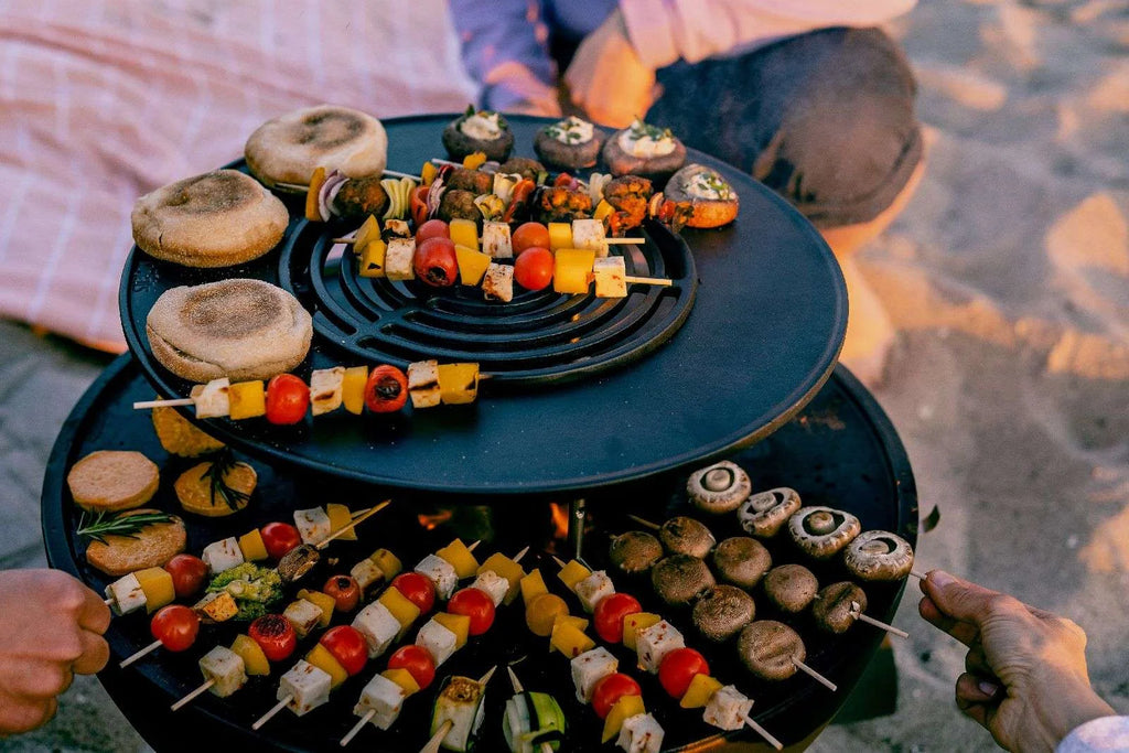 Plateau de service noir à étages avec brochettes colorées et assiettes pour les rassemblements en extérieur.