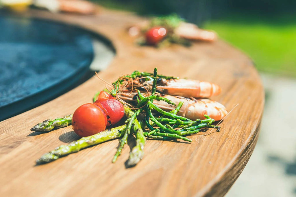 Planche de service en bois avec des asperges et des crevettes dessus.