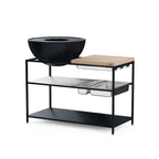 Support-grill en métal noir avec planche à découper en bois et plateau en verre, design moderne.