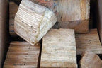 Bûches de bois de chauffage dans une boîte, apparence brun clair et usée.