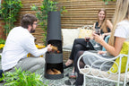 Cheminée extérieure cylindrique noire avec un design élégant et moderne et des compartiments pour bois empilés.