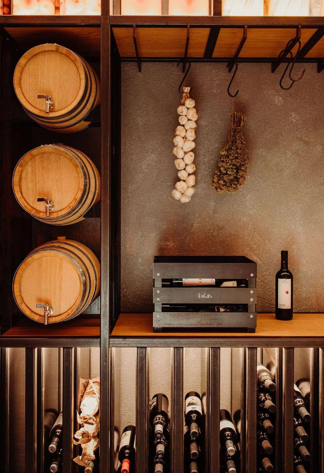 Casier à vin en bois sombre avec plusieurs bouteilles et barils, design rustique.