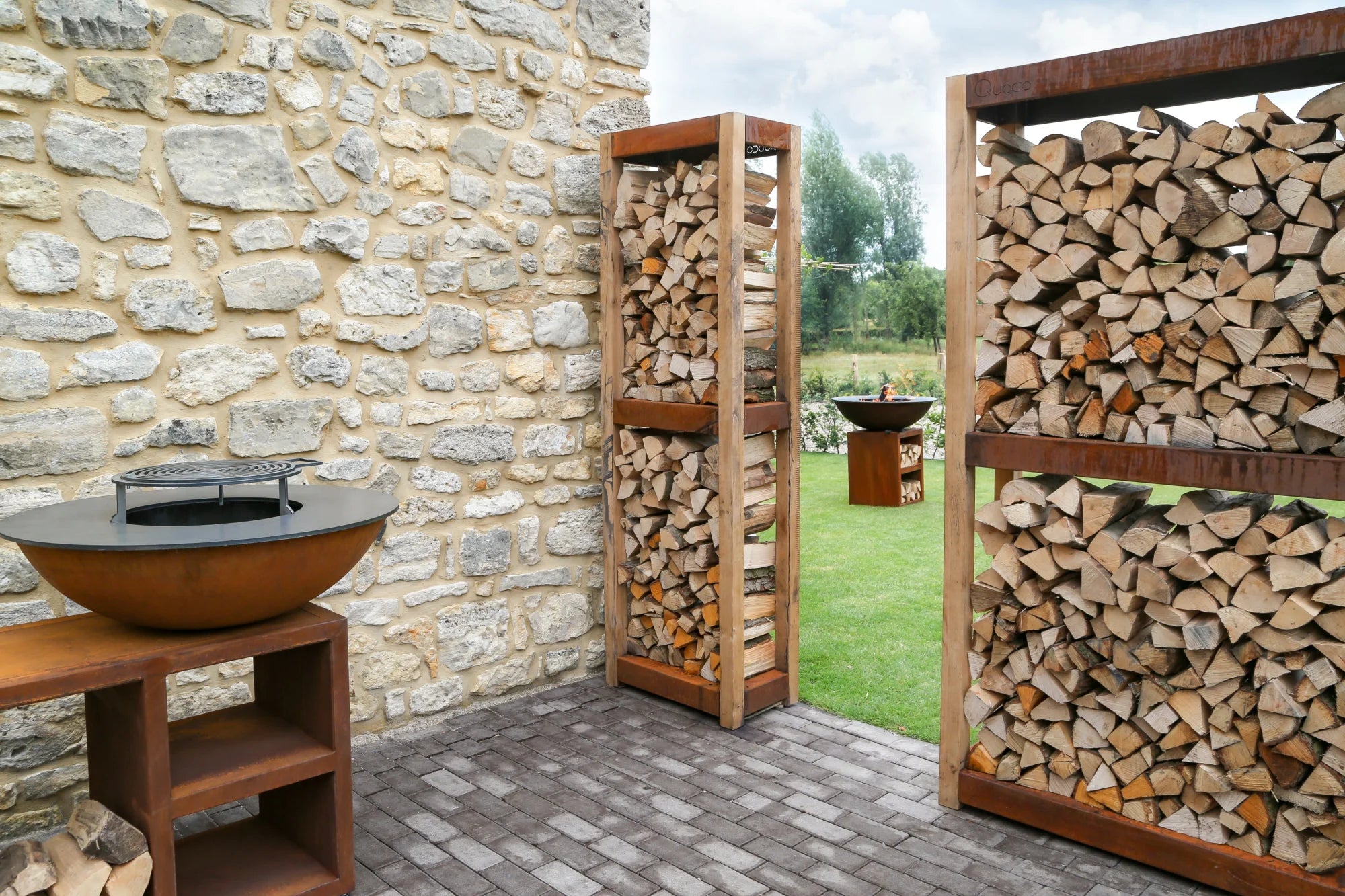 Gril en bol en cuivre rustique avec grille de cuisson noire sur un support en bois.