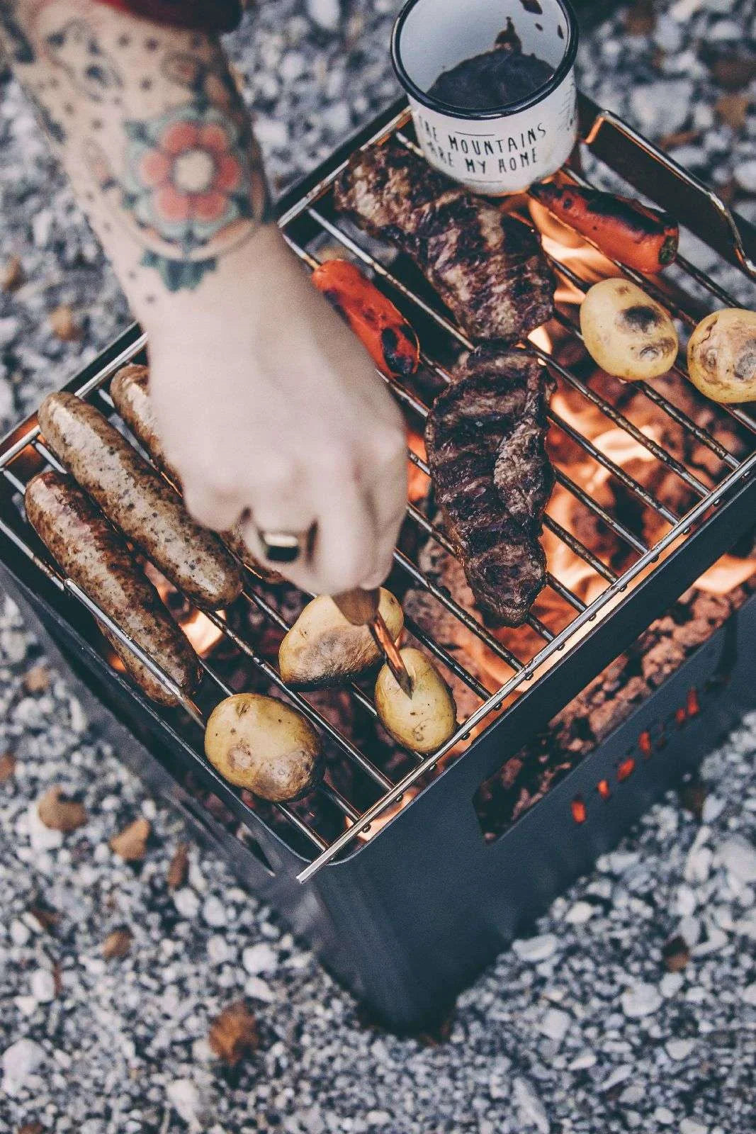 Barbecue au charbon avec grille en métal et bûches en bois pour la cuisson.