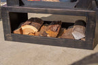 Organiseur de bois de chauffage en métal noir patiné, contenant des bûches empilées soigneusement.