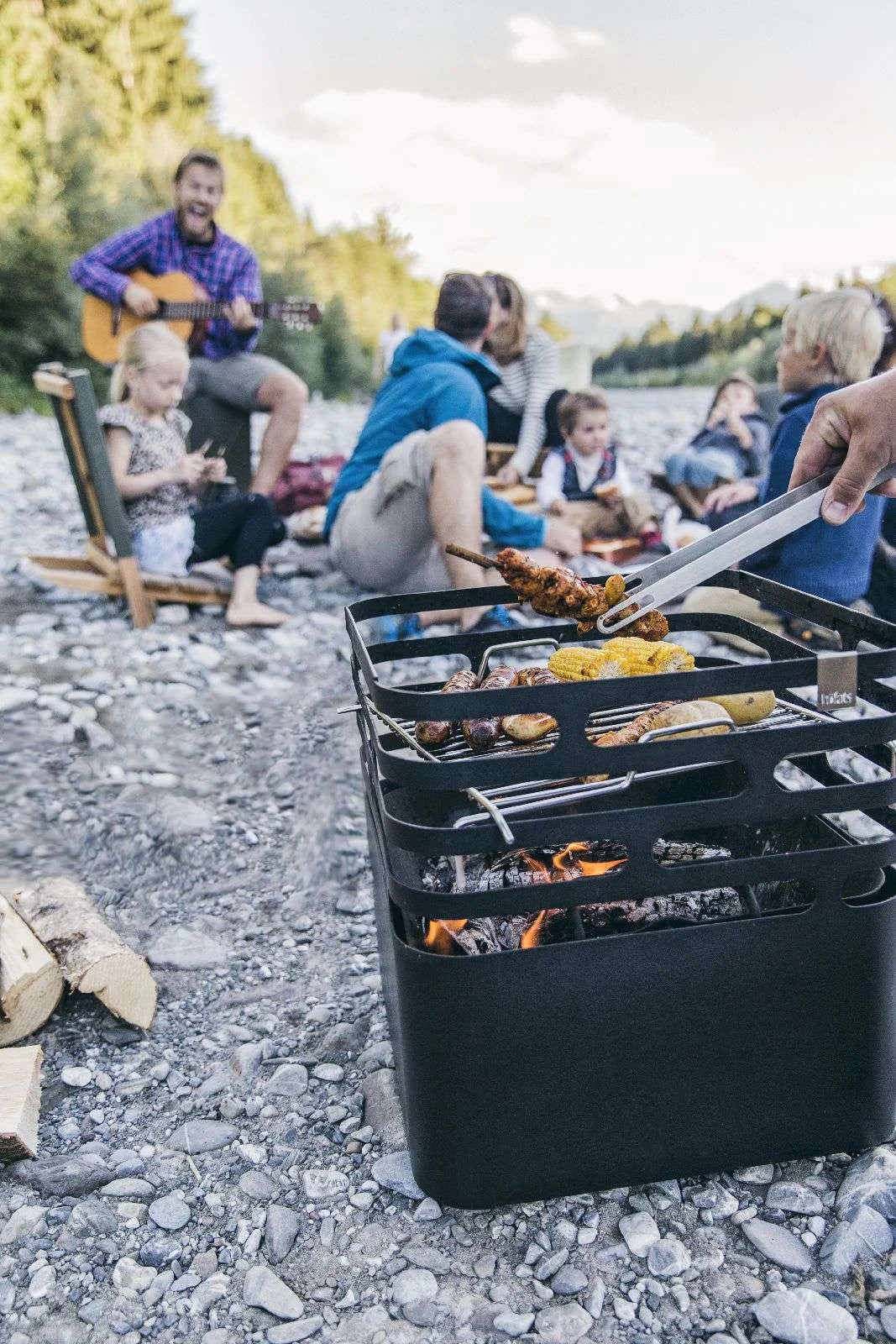 Barbecue portable noir avec plusieurs compartiments et poignées pour un transport facile.