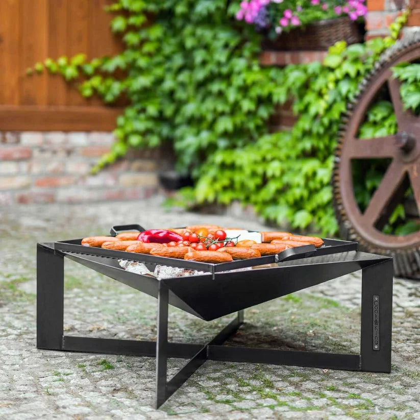 Gril carré noir avec pieds en métal et grilles, conçu pour la cuisson en extérieur.