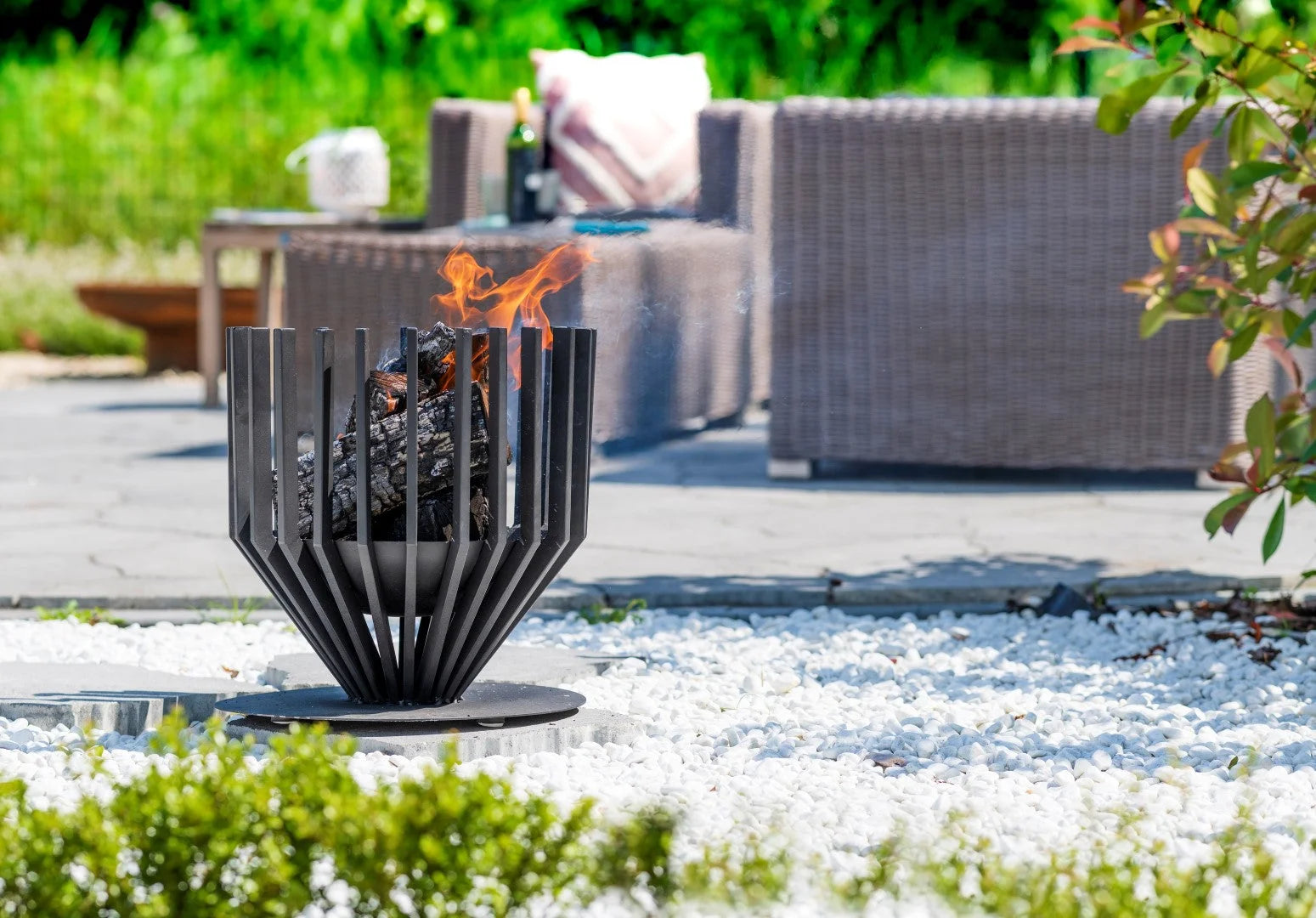 Foyer de feu en métal noir avec un design moderne en forme de pétales et des flammes brûlant à l’intérieur.