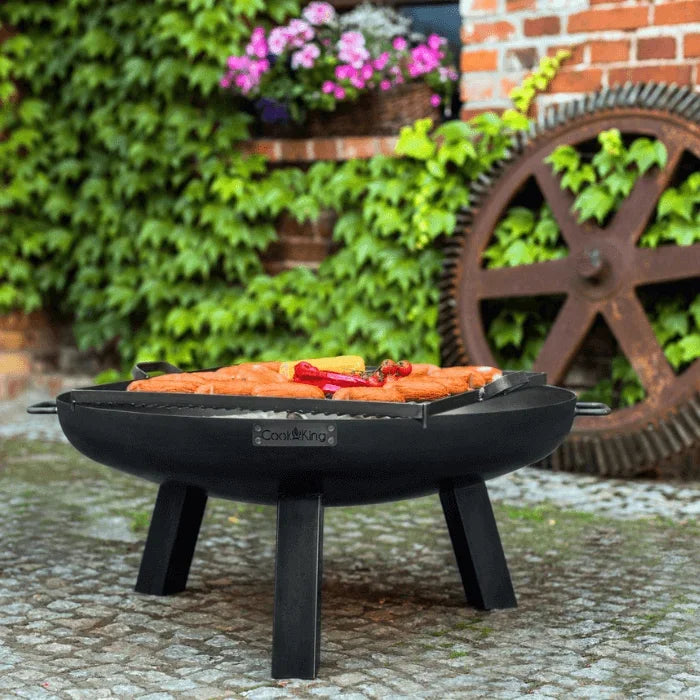Barbecue grill en fonte noire avec trois pieds et une poignée pour un transport facile.