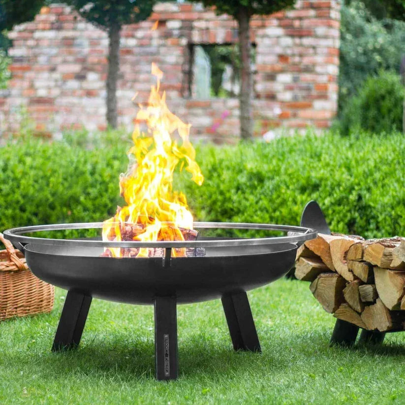 Foyer de feu noir avec des pieds en métal et un insert en verre, conçu pour un usage extérieur.