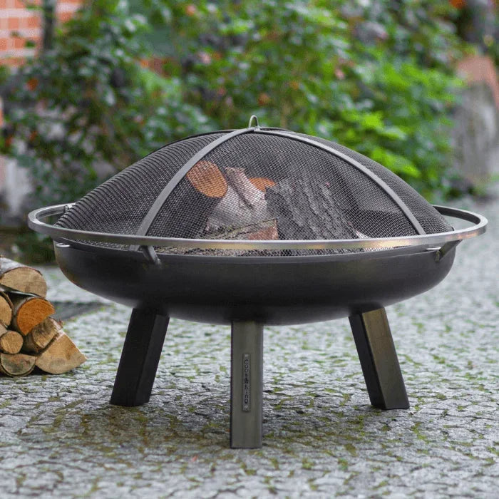 Foyer de feu en métal noir avec un écran en maille et trois pieds, conçu pour une utilisation en extérieur.