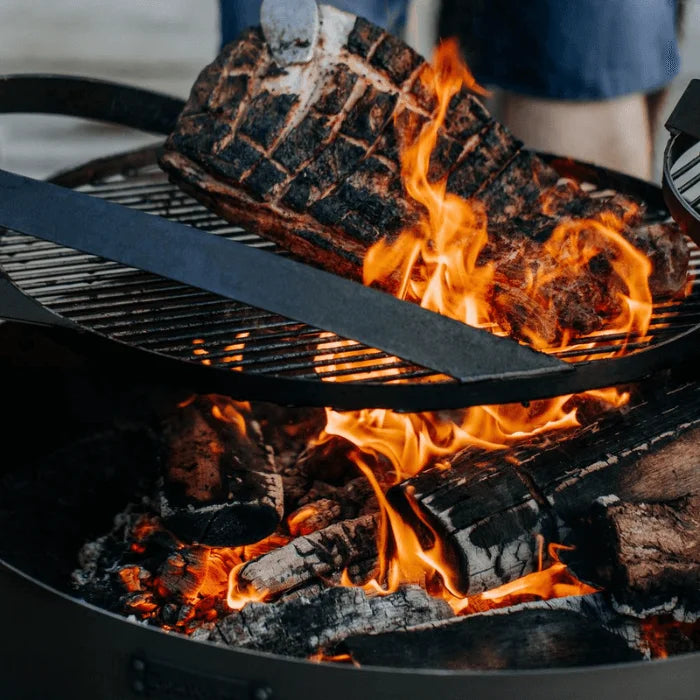 Barbecue au charbon avec grille noire et flammes vives.
