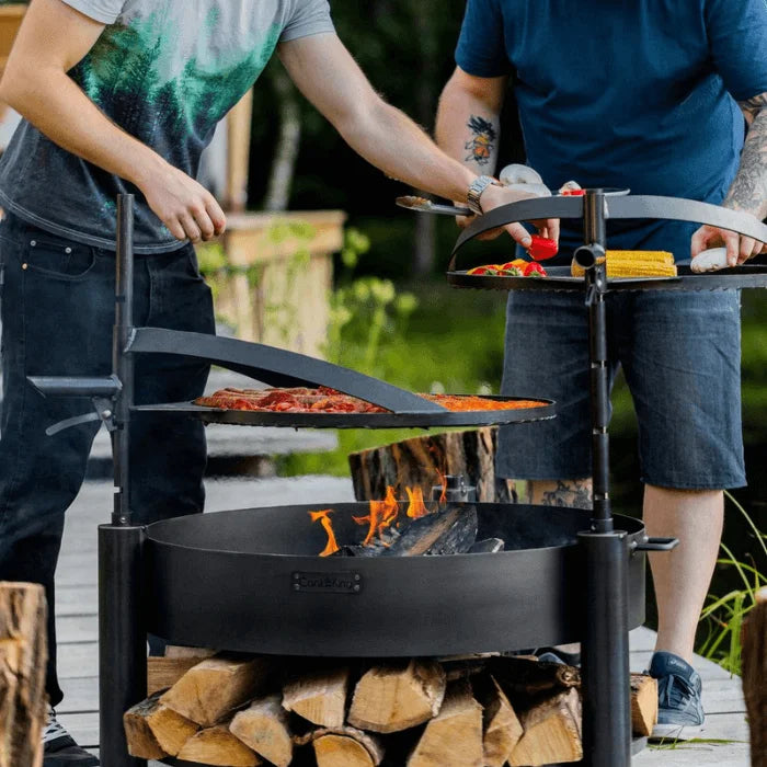 Gril en fonte noire avec base pour foyer et rangement pour bois.