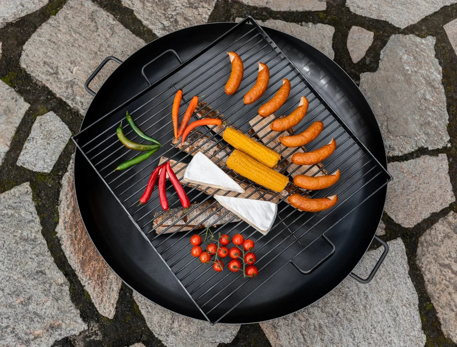 Gril rond noir avec grille en métal et poignées, conçu pour la cuisson en extérieur.