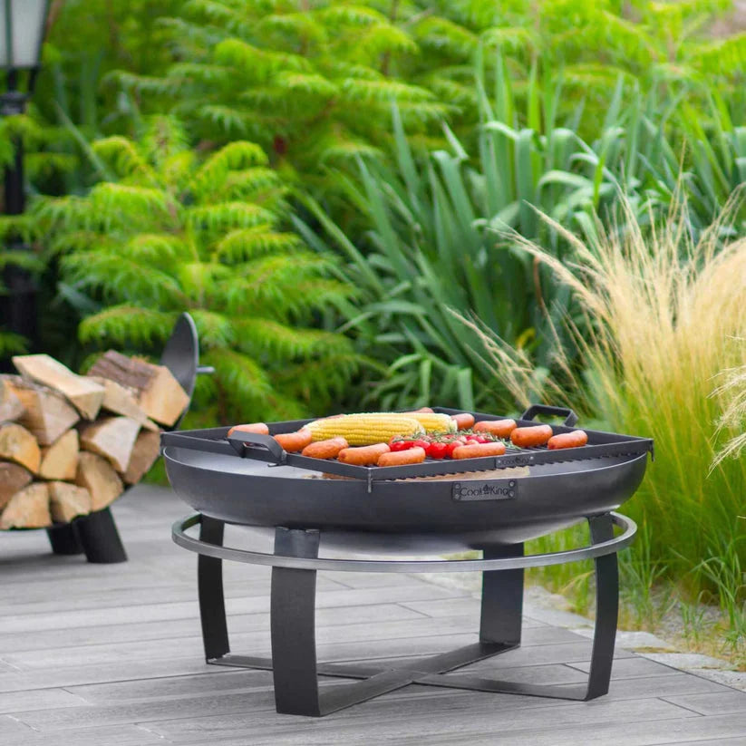 Barbecue extérieur en fonte noire avec pieds et poignée en métal, conçu pour griller des hot-dogs et du maïs en épi.