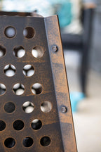 Panneau métallique rouillé avec une grille de trous circulaires et des boulons visibles.