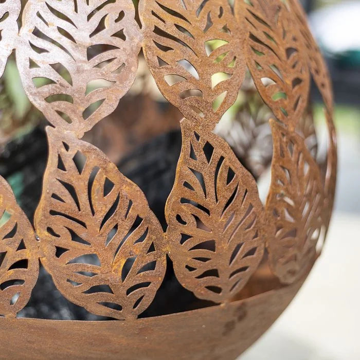 Pot sphérique en métal rouillé avec découpes de feuilles intricées