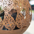 Pot sphérique en métal rouillé avec découpes de feuilles intricées