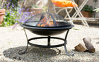Foyer de feu en fer forgé noir avec couvercle en maille et pieds courbés.