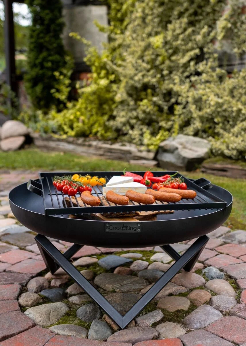Barbecue au charbon avec un cadre noir et une surface de cuisson ronde, comportant plusieurs grilles pour divers articles alimentaires.