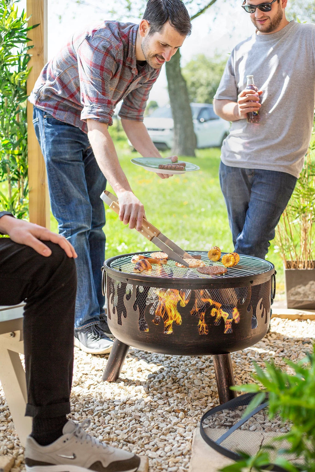 Foyer de feu en métal noir avec découpes en forme de flammes et trois pieds