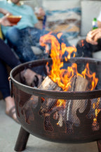 Foyer de feu en métal noir rustique avec découpes en forme de flammes et trois pieds