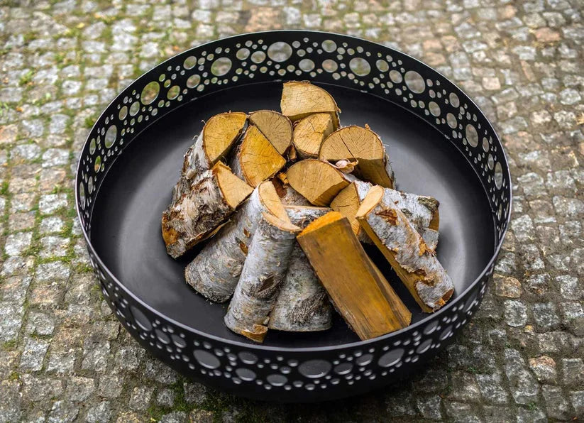 Porte-bûches en métal noir avec découpes décoratives et un design de bûche de bois rustique.