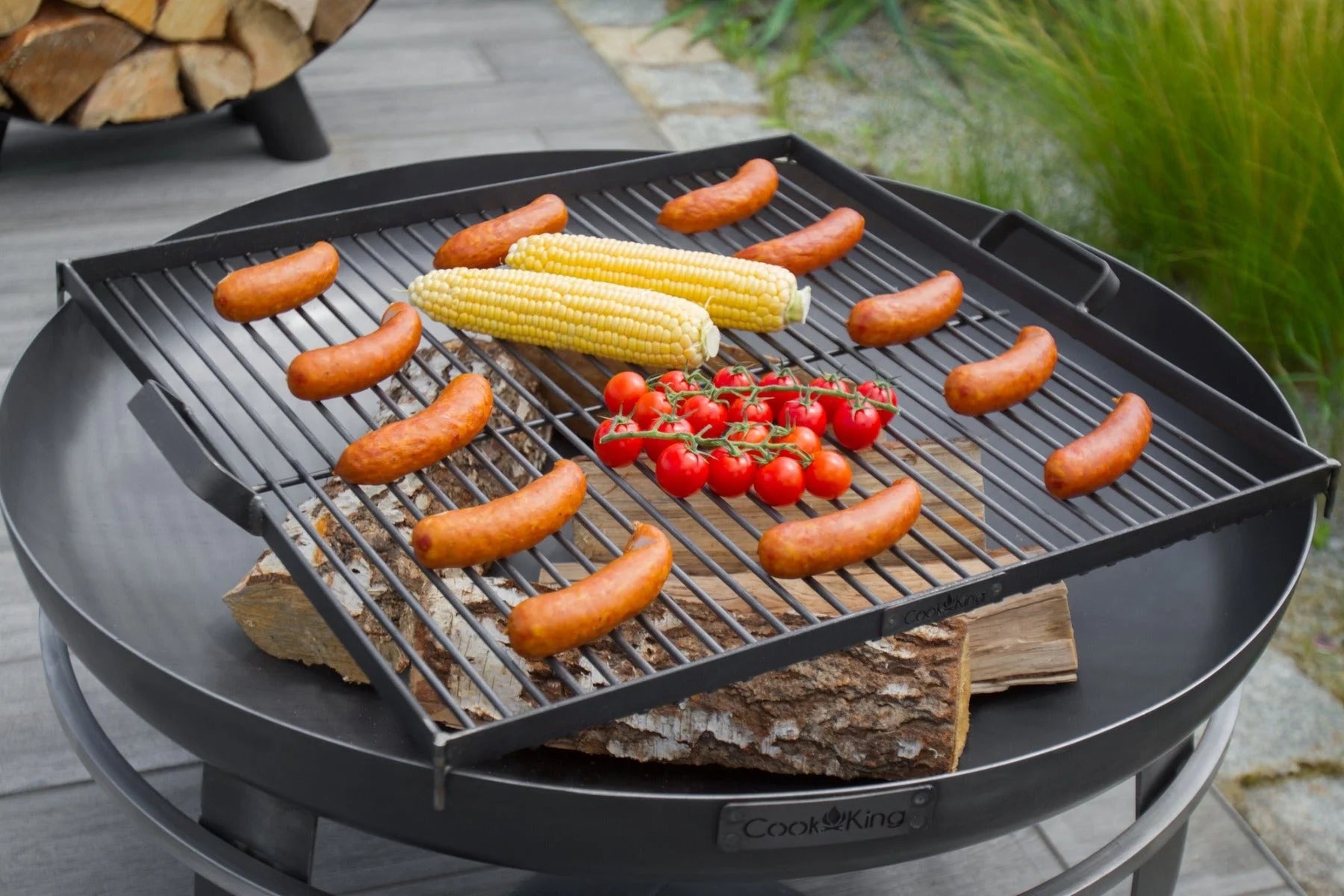 Gril en fonte noire avec plusieurs saucisses et légumes dessus.