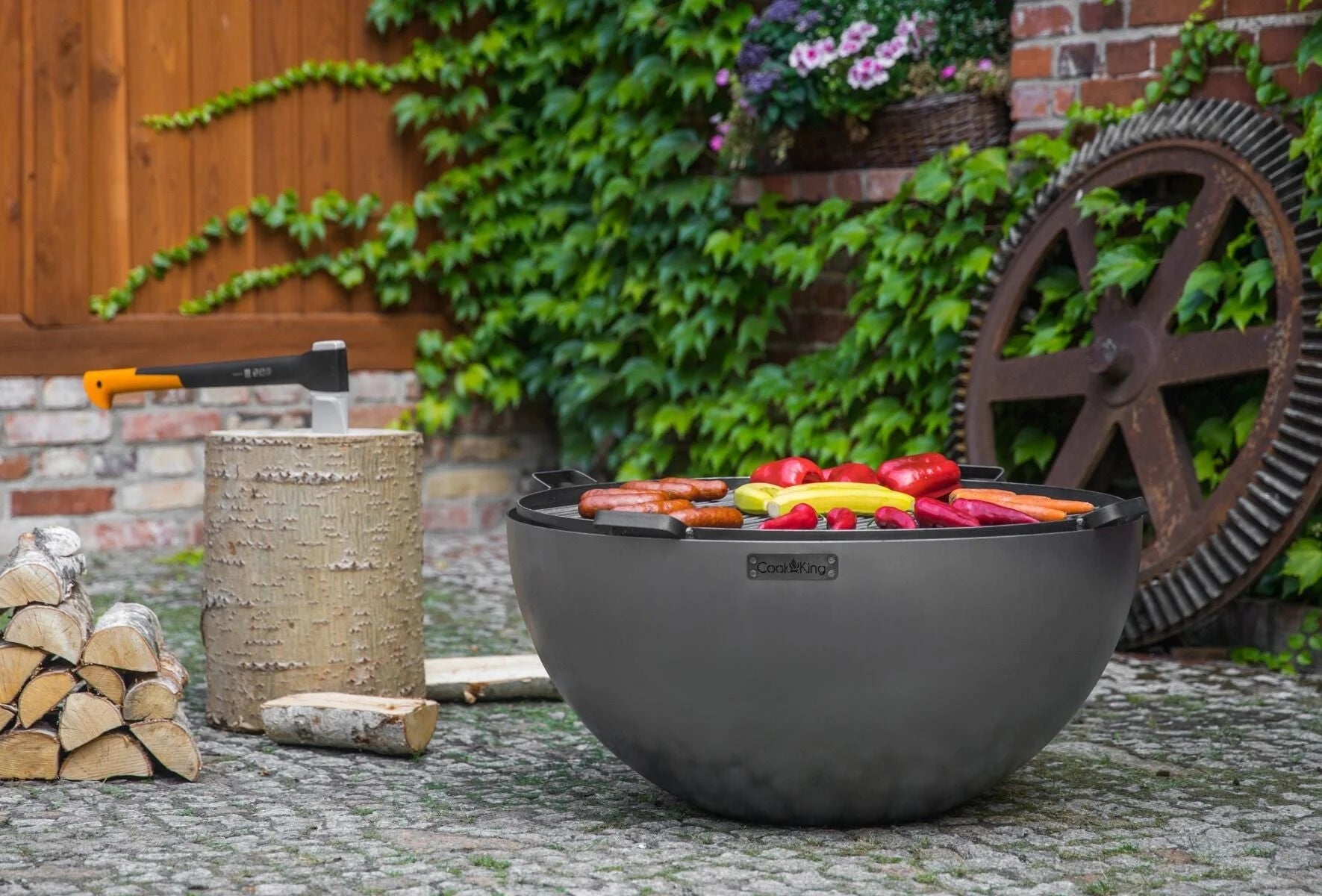 Gril en bol noir avec des légumes colorés et des copeaux de bois à l’intérieur, conçu pour la cuisson en extérieur.