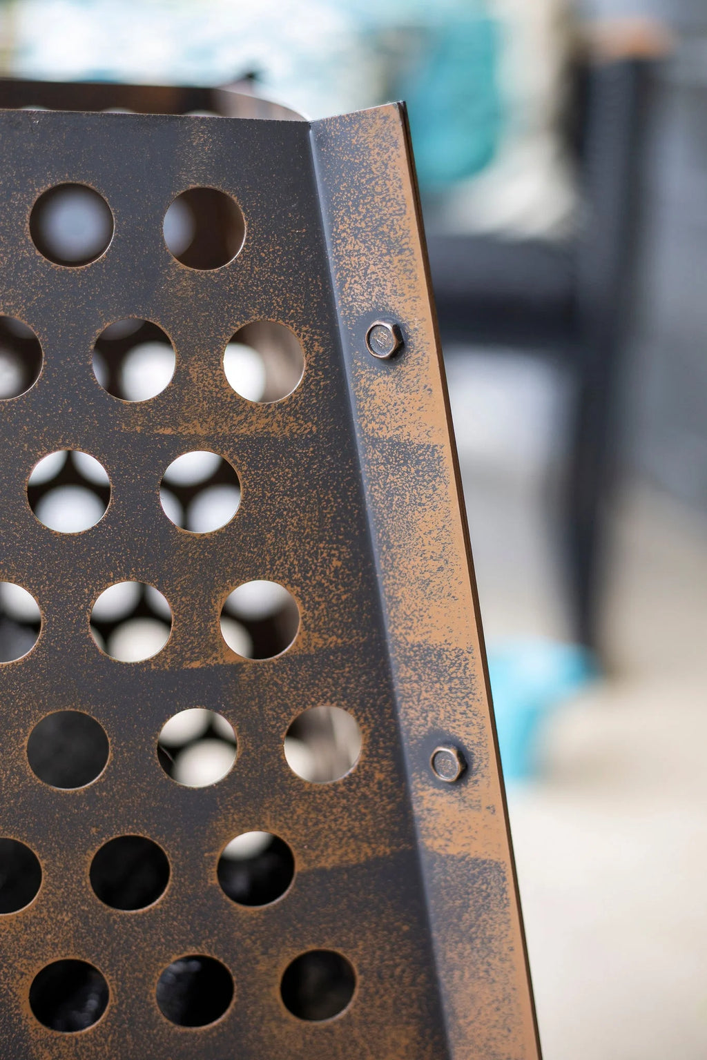Panneau métallique rouillé avec une grille de trous circulaires et des boulons visibles.