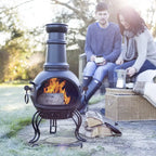 Chimenea en fonte noire avec une flamme brûlant à l’intérieur et des bûches empilées à proximité