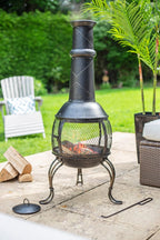 Chimenea en fer forgé noir avec écran en maille et flamme à l’intérieur