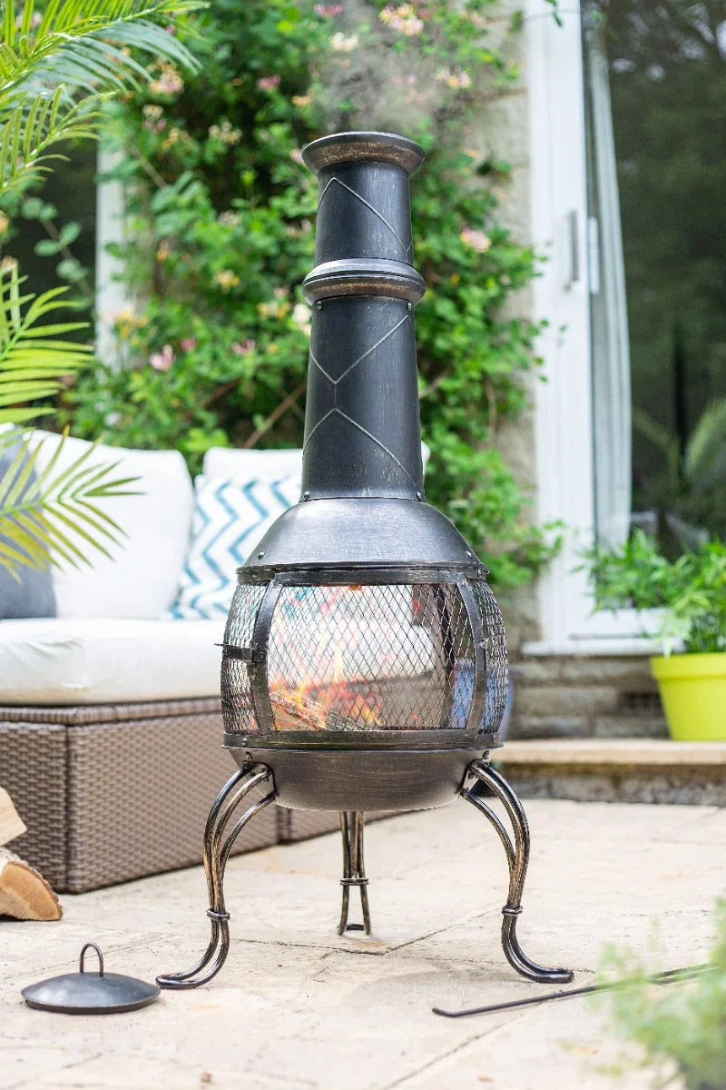 Chimenea en fonte noire avec un devant en maille et des motifs décoratifs en losanges sur la cheminée.