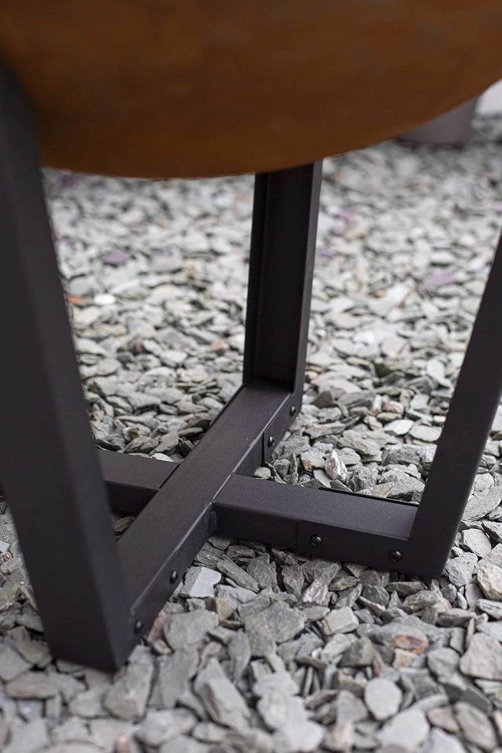 Cadre en métal noir avec des pieds angulaires soutenant un plateau circulaire de couleur rouille.