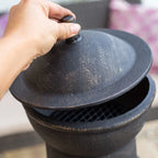 Barbecue extérieur en fonte noire avec un couvercle en dôme et une surface texturée.