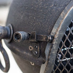 Logement de ventilateur en métal noir rustique avec une grille en maille et des points d’attache boulonnés.