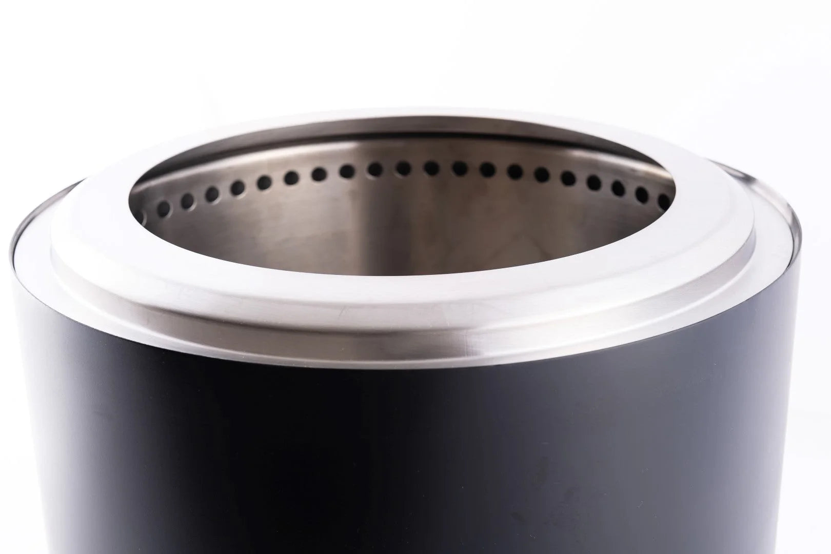 Foyer de feu extérieur cylindrique noir avec un rebord en acier inoxydable et un anneau intérieur perforé.