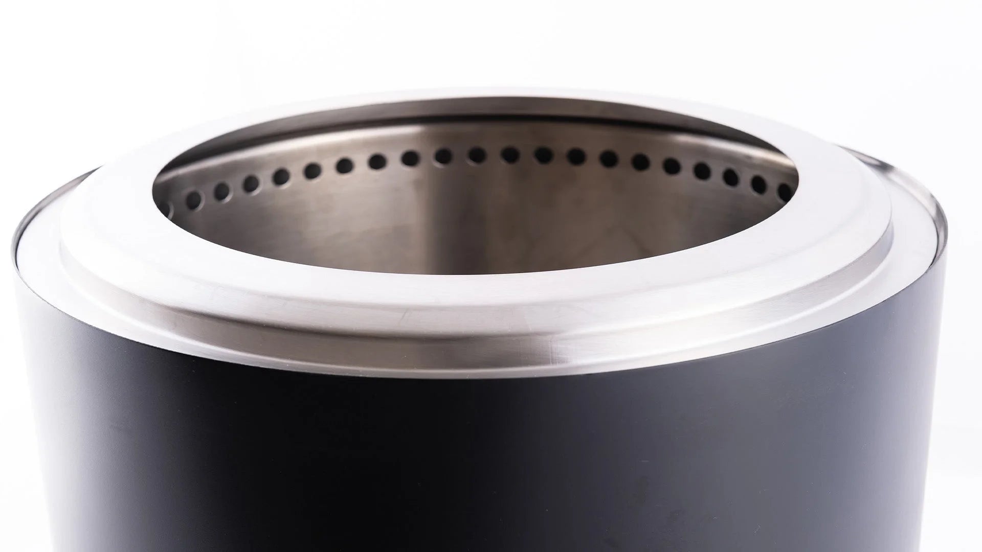 Foyer de feu extérieur cylindrique noir avec un rebord en acier inoxydable et un anneau intérieur perforé.