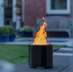 Foyer de feu extérieur cylindrique noir avec une flamme orange vibrante s’élevant de son sommet