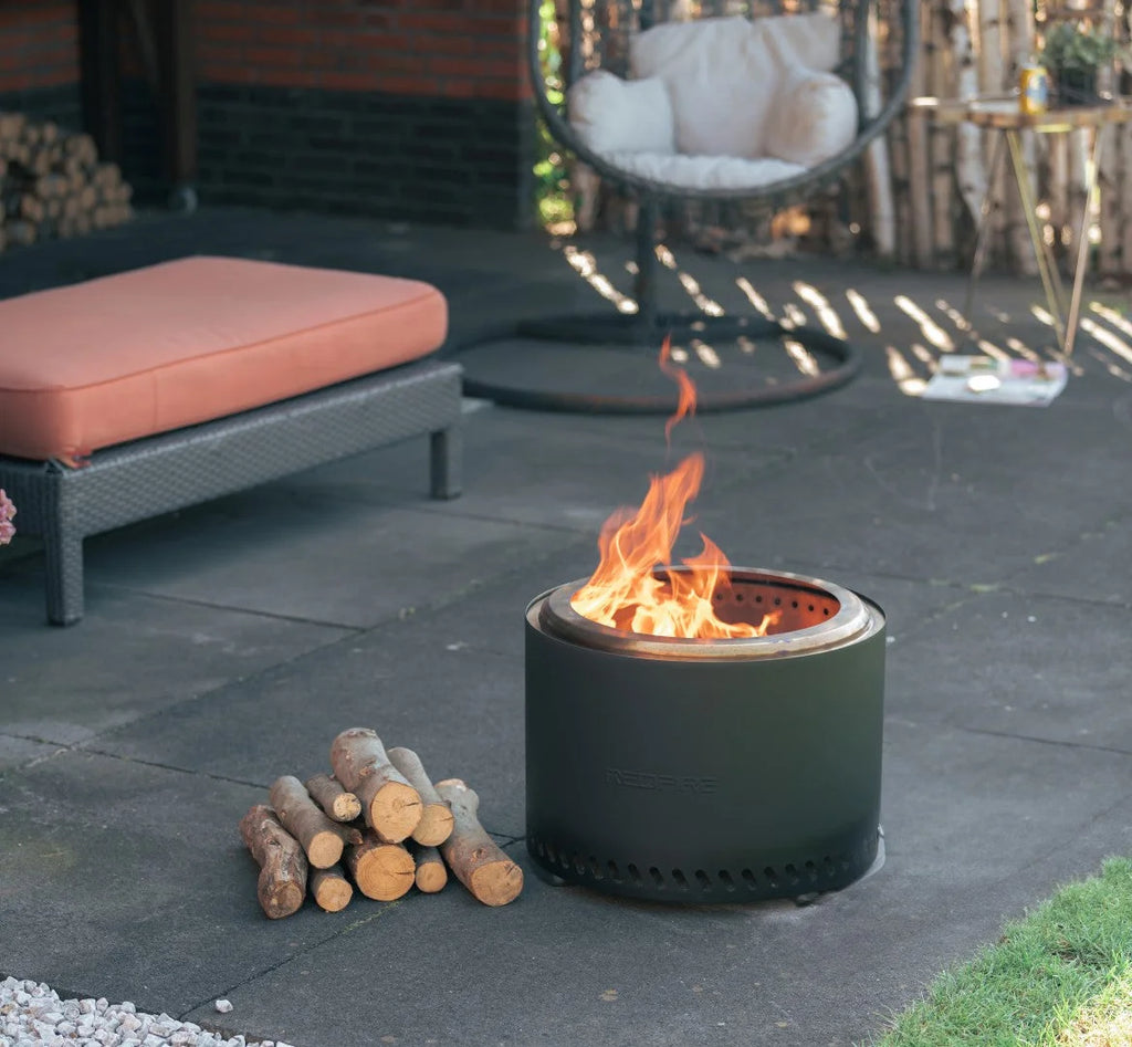 Foyer de feu cylindrique noir avec une flamme brûlant à l’intérieur et de petits trous de ventilation autour de sa base.