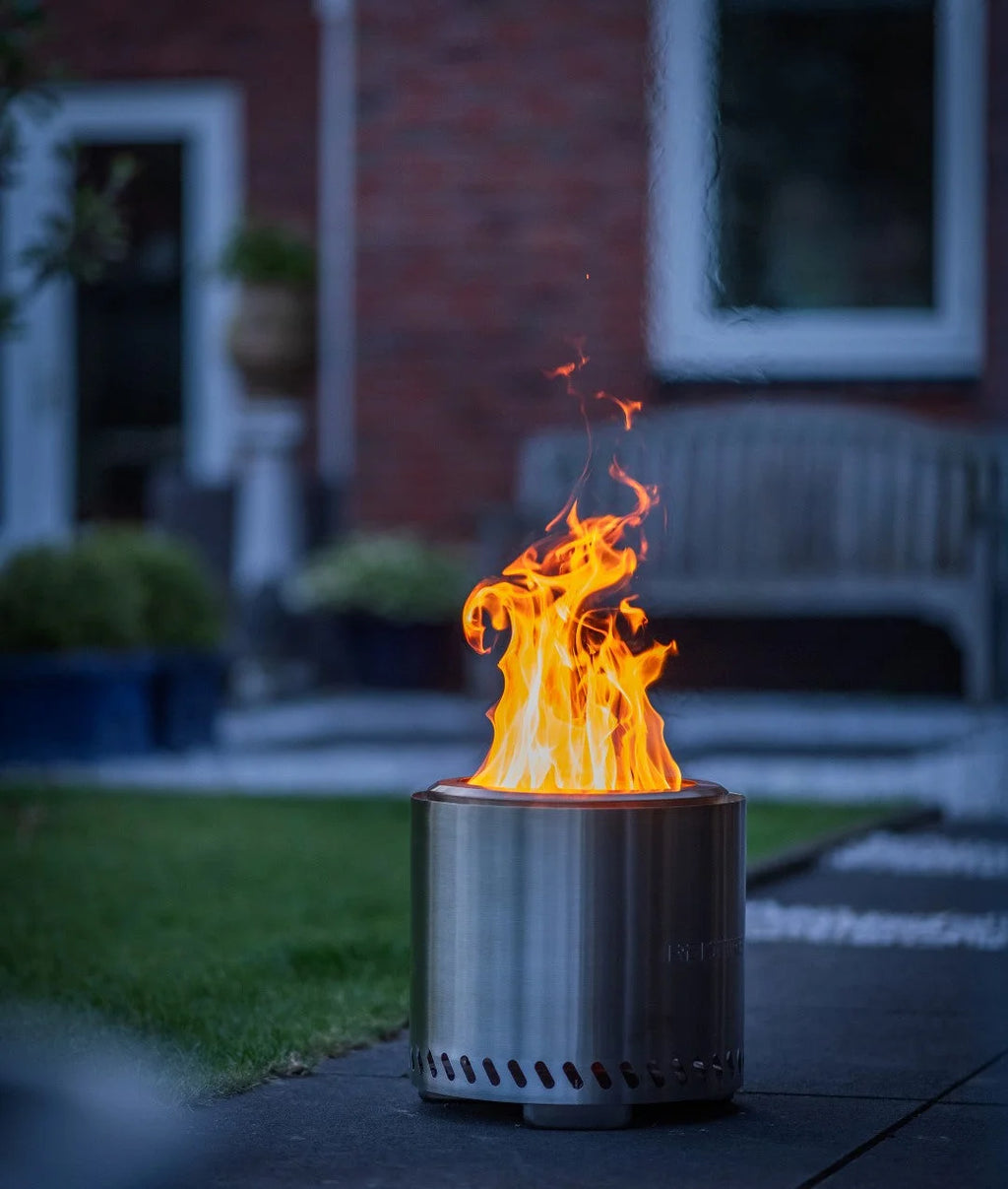 Foyer cylindrique en acier inoxydable avec une flamme orange vibrante s’élevant de son sommet.