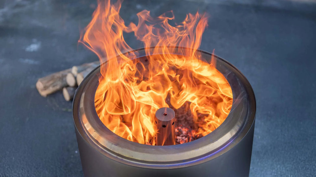 Un foyer de feu métallique cylindrique élégant avec une flamme orange vibrante dansant à l’intérieur de son ouverture circulaire.