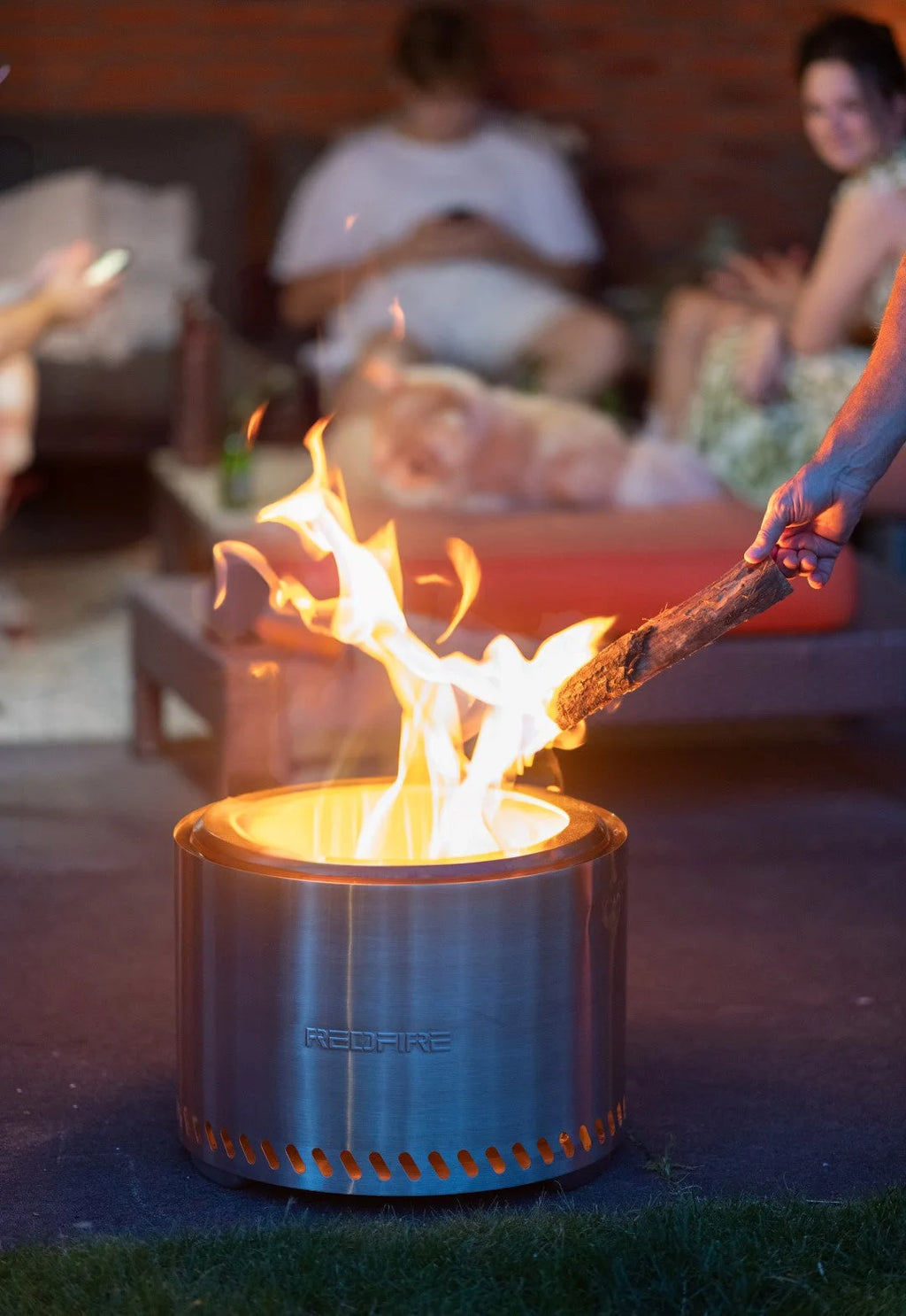 Foyer d’incendie cylindrique en acier inoxydable avec un design élégant et moderne et le nom de marque « redfire » gravé sur son côté.