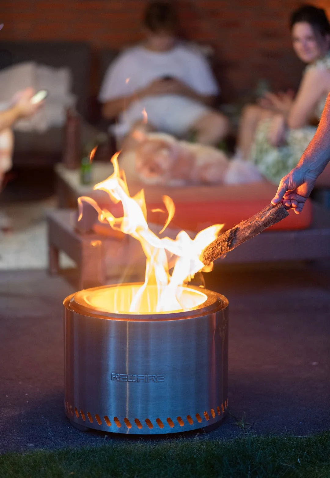 Foyer d’incendie cylindrique en acier inoxydable avec un design élégant et moderne et le nom de marque « redfire » gravé sur son côté.