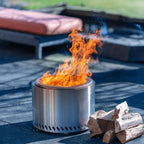 Un foyer de feu cylindrique élégant en acier inoxydable avec un design moderne et des fentes de ventilation le long de sa base.
