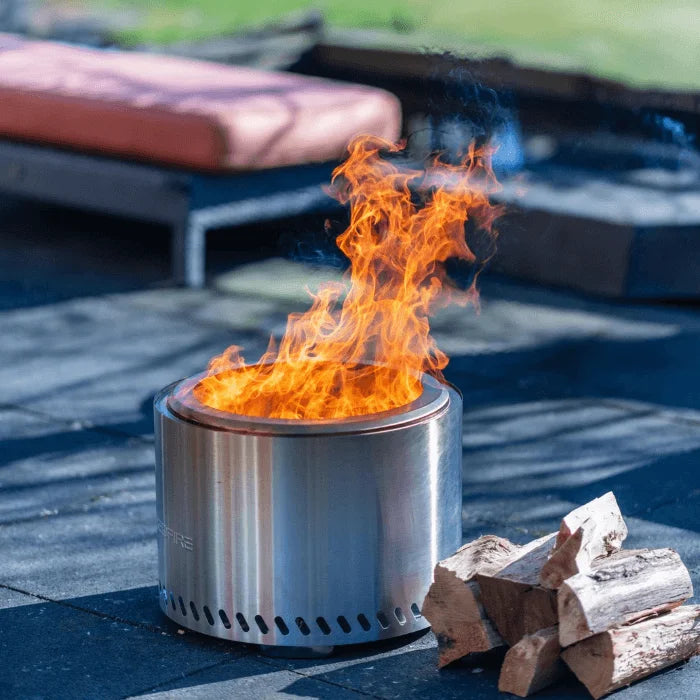 Un foyer de feu cylindrique élégant en acier inoxydable avec un design moderne et des fentes de ventilation le long de sa base.