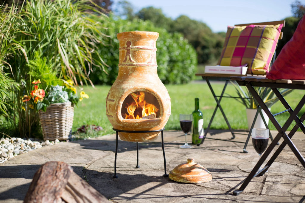 Chimenea en terracota avec un glaçage orange-brun chaud et des motifs sculptés décoratifs, présentant un feu ouvert à l’intérieur.