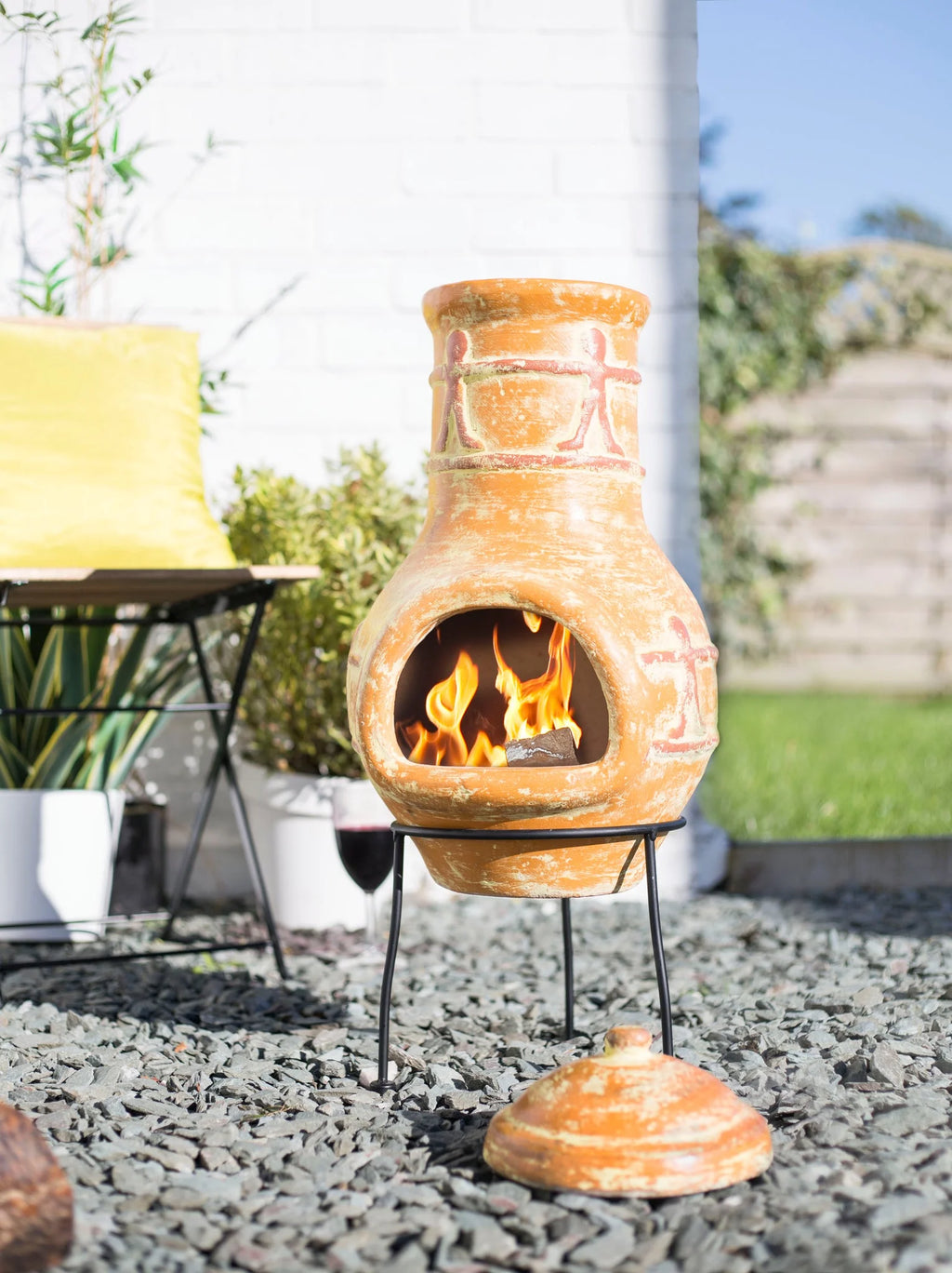Chimenea en terracota avec un glaçage orange-brun chaud et des motifs géométriques rouges peints à la main, présentant une chambre de combustion ouverte au centre.